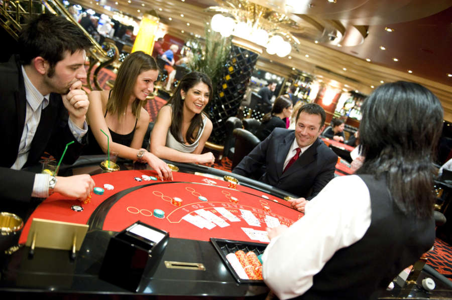 People enjoying a lively casino on a cruise ship, with slot machines, gaming tables, and vibrant lighting creating an exciting atmosphere.