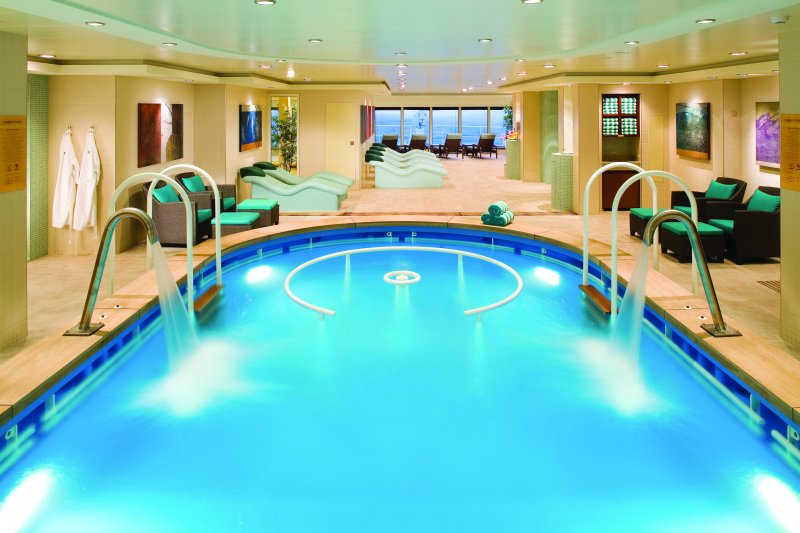 Guests relaxing in the indoor pool at the public spa on the NCL Pearl cruise ship, enjoying the serene and luxurious environment.