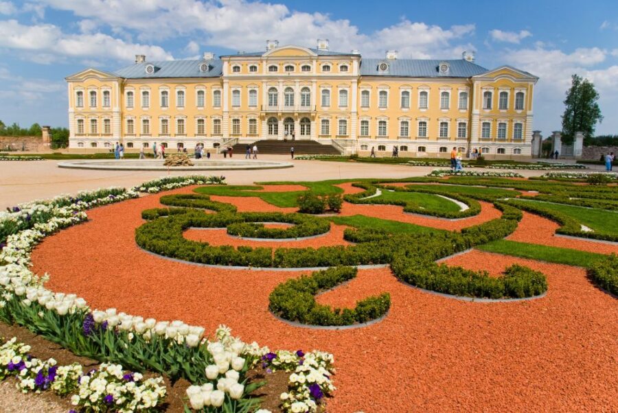 Rundāle Palace, a stunning example of Baroque architecture, featuring a yellow facade and ornate gardens.