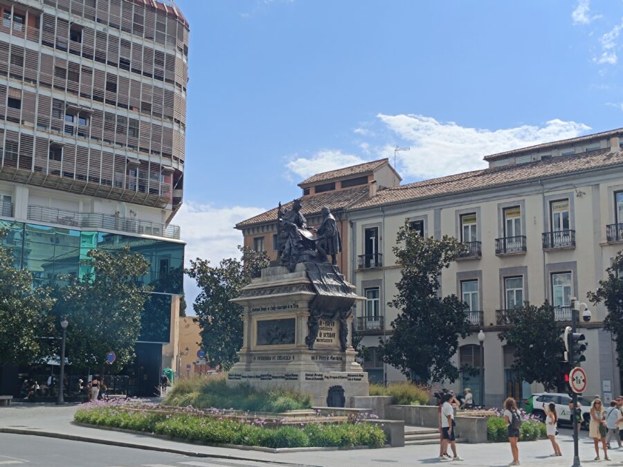 A view of Plaza de Isabel la Católica in Granada, Spain, featuring the monument to Isabella I of Castile and Ferdinand II of Aragon.