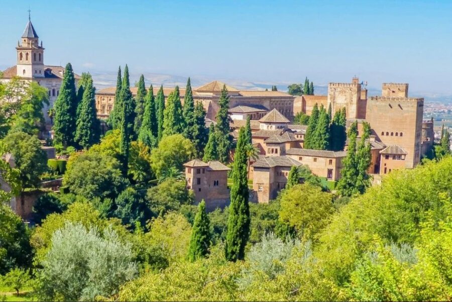Majestic Alhambra Palace in Granada, Spain, surrounded by lush cypress trees and ancient walls, showcasing stunning Moorish architecture.