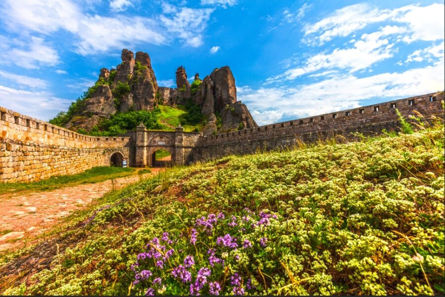 Impressive ancient Belogradchik Fortress in Bulgaria, perched amongst unique rock formations under a vibrant blue sky with fluffy white clouds. Explore the rich history and stunning landscapes of the Balkans.