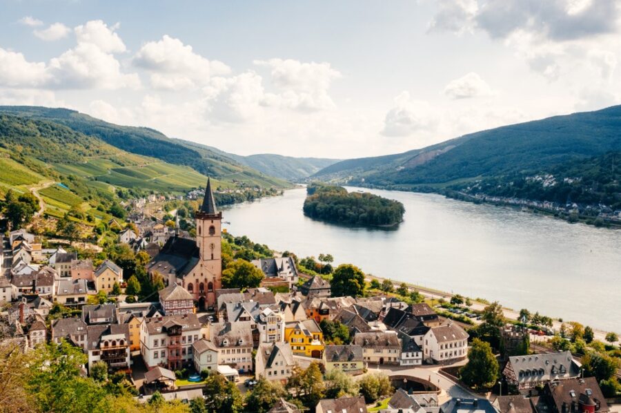 Stunning panoramic view of Lorch, Germany, nestled in the Rhine Valley. Quaint buildings with a prominent church tower overlook the river and surrounding vineyards. Discover the romantic Rhine on a European river cruise.