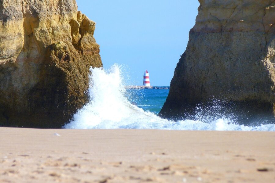 Lighthouse on the Algarve between 2 Cliffs with wave crashing onto the cove like beach
