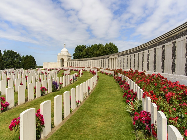A wide view of the curved memorial wall and rows of white headstones at Tyne Cot Cemetery in Flanders.