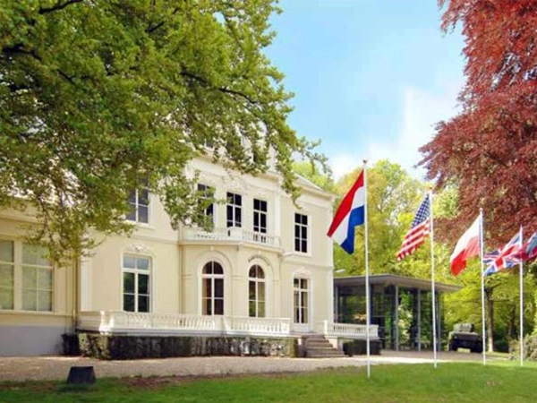 The Airborne Museum Hartenstein in Oosterbeek, Netherlands, with Dutch, American, Polish, and British flags flying.