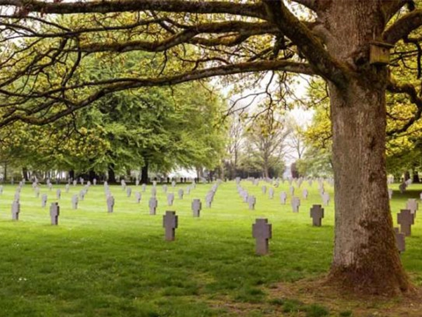 The Recogne German War Cemetery near Bastogne, showing dark stone crosses on a green lawn.