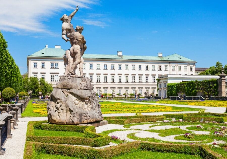 Mirabell Palace and Gardens in Salzburg, Austria. A majestic baroque palace with a dramatic statue and vibrant flowers.