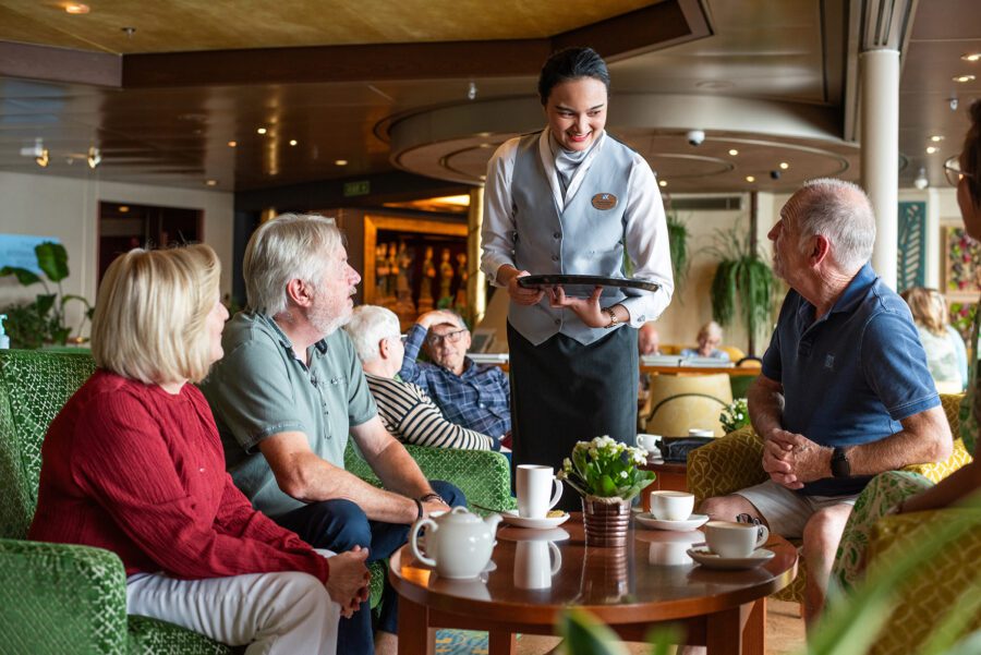 Guests enjoying tea and conversation with friendly cruise staff on MS Bolette