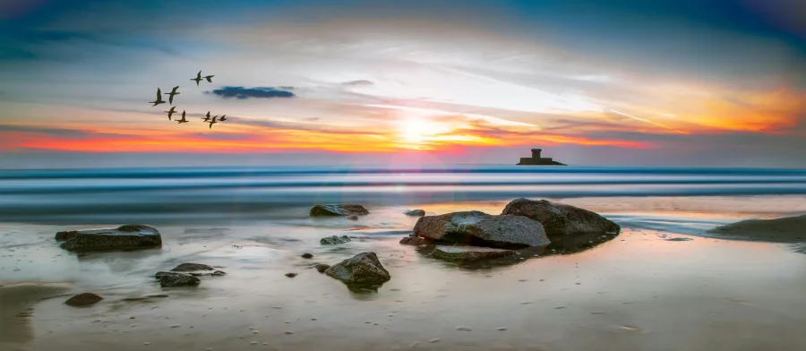 A peaceful sunset view over the golden sands and calm waters of a Jersey beach.