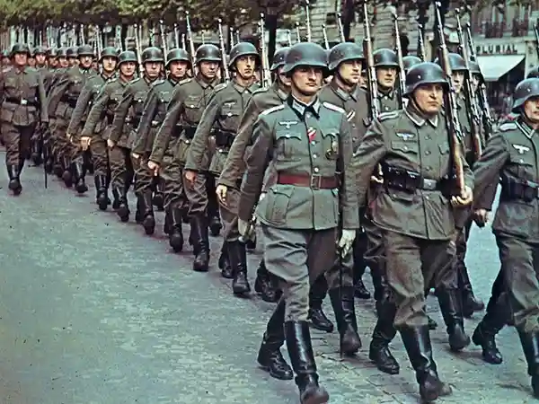 A historical colorized photograph of German soldiers marching in formation, representing the history uncovered on our WW2 Secrets of the Third Reich tour in Munich.