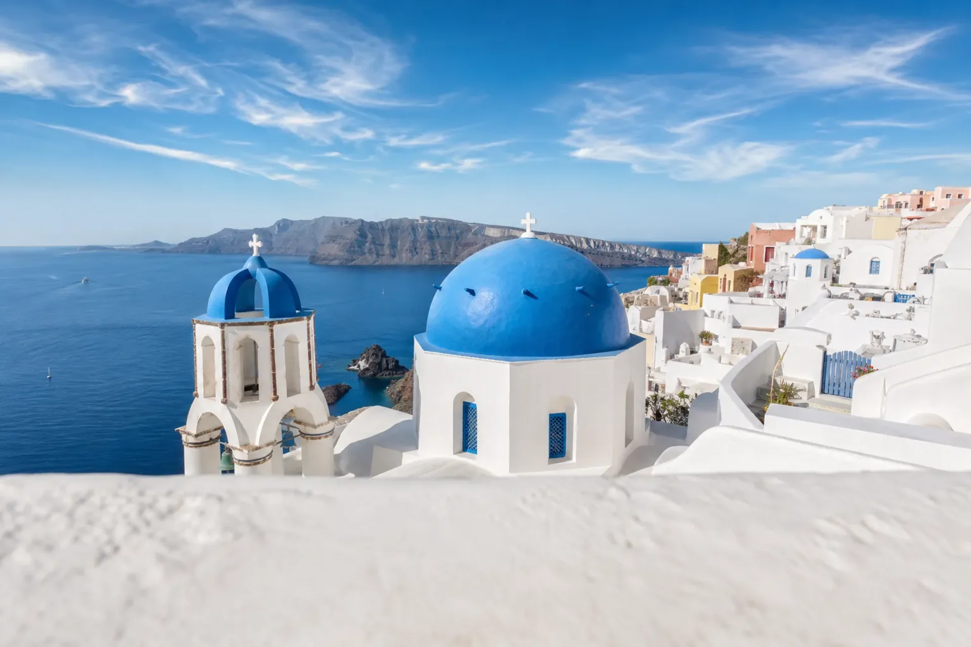 Greece and Turkey-A sun-filled view of the blue domes and white buildings of Santorini, a key stop on our Greek Isles Turkey cruise.