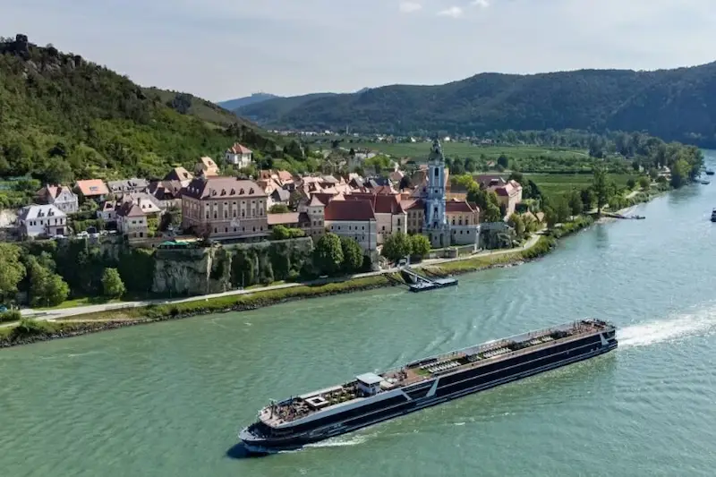 Aerial view of a contemporary Travelmarvel river cruise ship sailing past a historic European river town