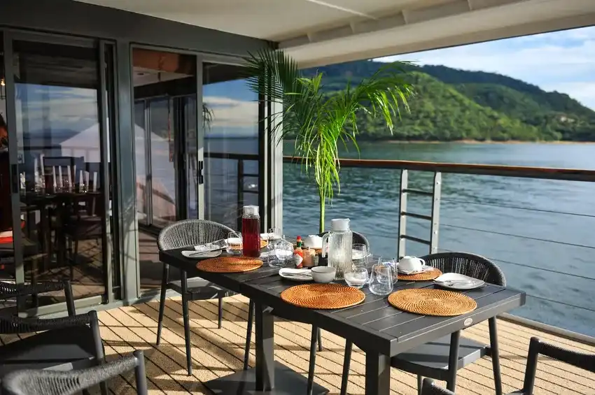 Outdoor dining terrace on the CroisiEurope African Dream boutique river cruise ship overlooking scenic river hills