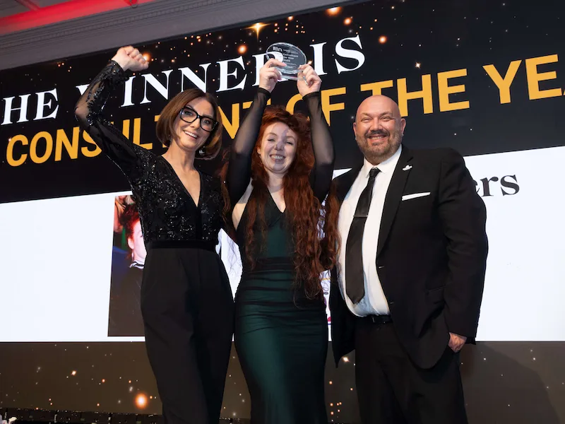 Travel Escapes holding up their award trophy on stage alongside celebrating colleagues after winning Travel Consultant of the Year at the ITTN Awards