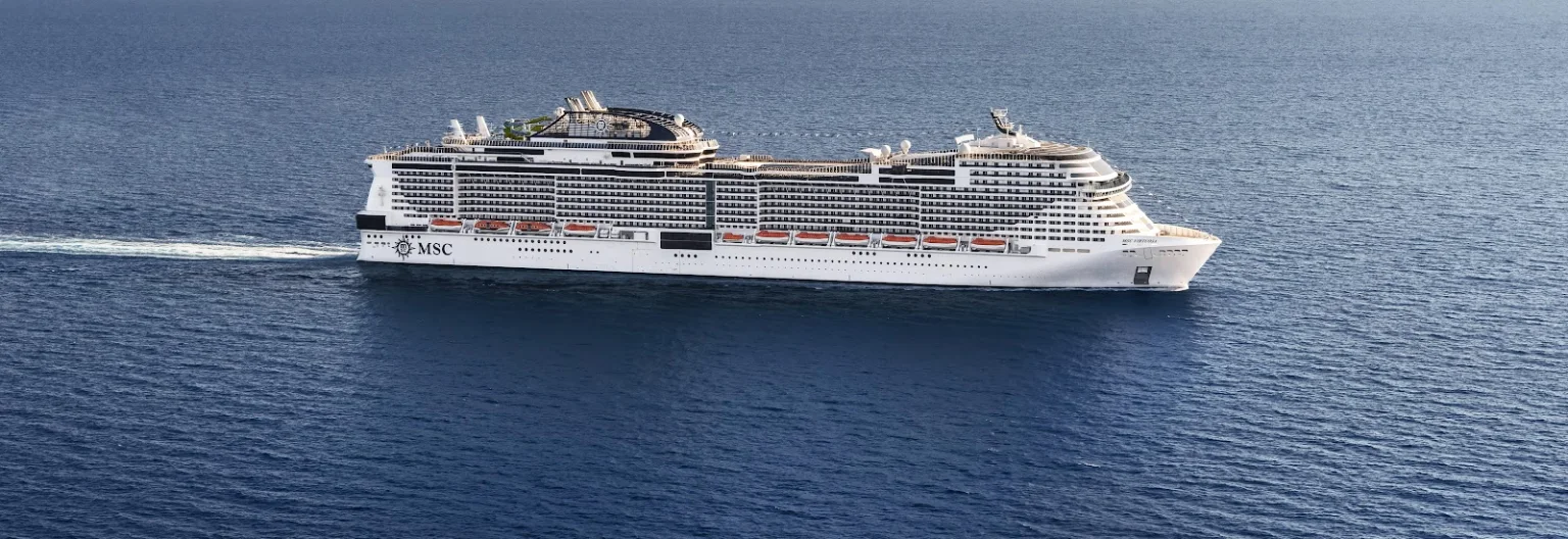 Aerial view of the MSC Virtuosa cruise ship sailing through calm blue ocean waters.