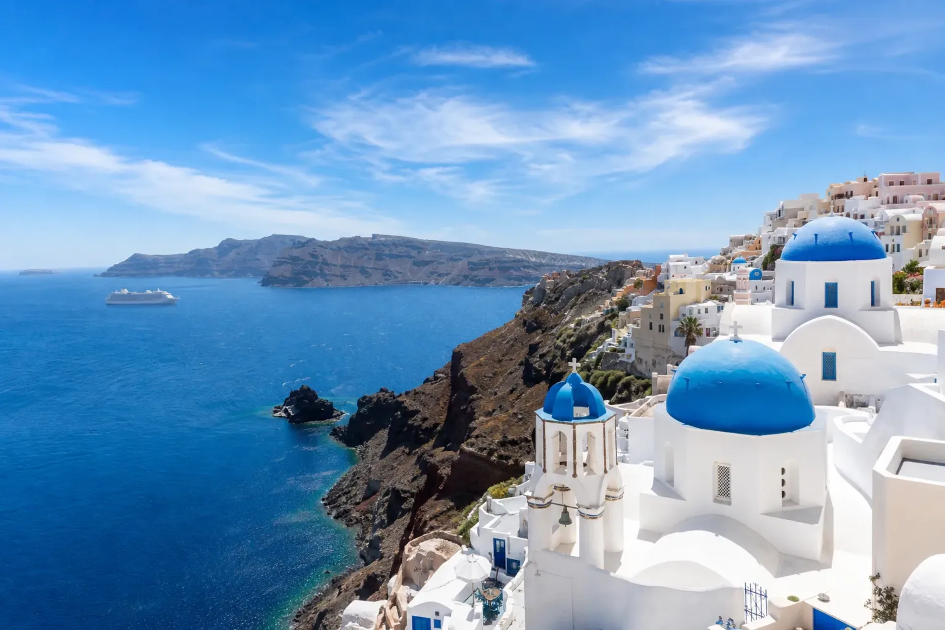 Greece & Italy-A stunning view of Santorini during a Greece Italy Cruise with a generic passenger ship on the horizon.